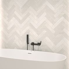 a white bath tub sitting next to a wall with a chevron pattern on it