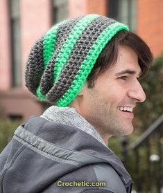 a man wearing a green and gray crochet hat with a smile on his face