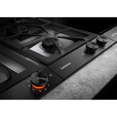 a black stove top sitting on top of a counter next to a cup with an orange light in it