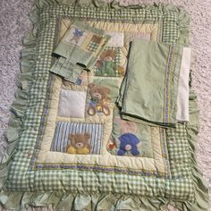 a quilted blanket with teddy bears on it sitting on the floor next to pillows and blankets