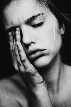 a black and white photo of a woman holding her hand to her face with both hands