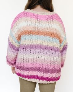 This sweater is a cozy, oversized knit cardigan with a gradient color pattern. It features a variety of pastel and muted hues, blending seamlessly from one color to the next. The color palette includes shades of pink, purple, beige, and hints of blue and green, creating a soft and dreamy appearance. The knit fabric is chunky and textured, providing warmth and a comfortable fit. The sweater has a loose, relaxed silhouette with dropped shoulders and wide sleeves, giving it an effortlessly chic and Pink Knitted Sweater For Layering, Oversized Soft Knit Multicolor Cardigan, Pink Chunky Knit Sweater For Layering, Oversized Knitted Pink Outerwear, Pastel Knit Sweater For Fall, Oversized Multicolor Sweater For Layering, Oversized Pink Layering Sweater, Oversized Pink Sweater For Layering, Oversized Pink Knitted Cardigan