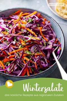 a bowl filled with coleslaw and carrots on top of a blue table