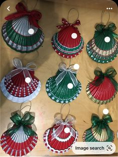 christmas ornaments are hanging on the wall with ribbons and bows around them, as if they were seashells