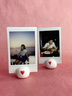 two polaroid frames sitting next to each other on a pink surface with hearts in the middle