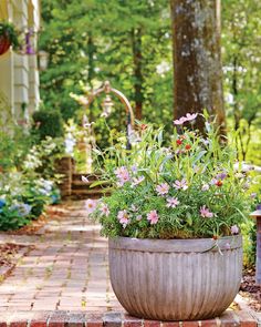 a planter filled with lots of flowers sitting on top of a brick walkway