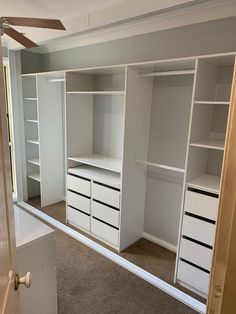 an empty room with white shelves and drawers