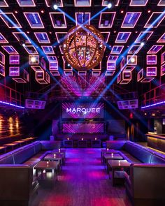 the marquee nightclub is lit up with purple and blue lights, as well as wooden benches