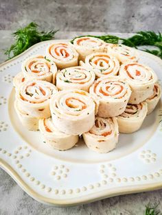 a white plate topped with rolls covered in cream cheese and carrots on top of a table