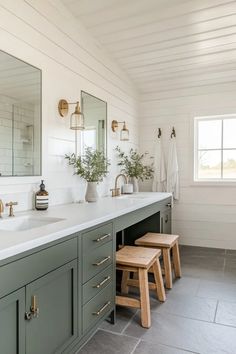 a bathroom with two sinks, mirrors and stools