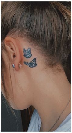 a woman with butterfly tattoos on her neck and behind her ear, looking down at the ground