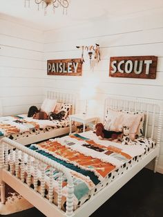 two beds in a room with white walls and wooden signs above them that read paisley scout