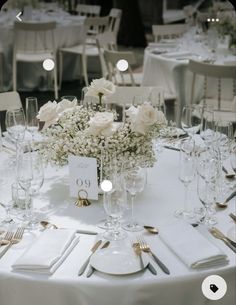 the table is set with white flowers and place settings for guests to sit down at