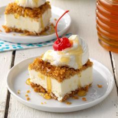 two pieces of cake on plates with cherries and whipped cream