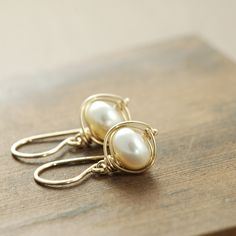 Lustrous white pearls are wrapped with 14k gold filled wire in these simple yet stunning earrings. These are extremely versatile and are easily dressed up or down. I love how the wire frames the luminous pearls... This is one of my favorite styles. The earrings fall a little over 1 inch (2.6 cm) from the very tops of the earwires and are about 7/16 inch (1.1 cm) at their widest points. Pearls are June's birthstone, so these make a great gift for someone with a birthday or anniversary in that mon Elegant Gold Wire Wrapped Wrap Earrings, Elegant Wire Wrapped Earrings For Everyday, Elegant Everyday Wire Wrapped Earrings, Minimalist Wire Wrapped Pearl Drop Earrings, Yellow Gold Wire Wrapped Pearl Earrings Gift, Wire Wrapped Yellow Gold Pearl Earrings Gift, Gold Wire Wrapped Pearl Earrings For Gift, Dainty Wire-wrapped Pearl Earrings For Gift, Dainty Wire Wrapped Pearl Earrings For Gift