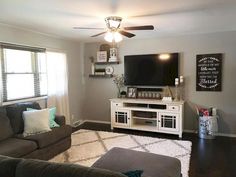 a living room with gray couches and a flat screen tv mounted on the wall