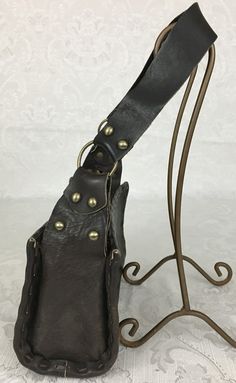 "Here we have a vintage brown leather footed Purse with a wide strap, metal studs and large buckle. This has a great retro look. This is in very nice condition considering its age. I noticed some light scratches but no ther problems. It measures: Height - 6\" Width - 9 3/4\" Depth - 4 1/4\" Strap Drop - 11 1/4\" I try my best to give accurate descriptions, although I am no expert, plus I'm human and sometimes I might miss a flaw. I always provide high resolution photos and consider them to be pa Brown Leather Shoulder Bag With Buckle Closure, Leather Satchel Shoulder Bag With Rivets, Vintage Leather Bags With Metal Hardware, Vintage Brown Faux Leather Shoulder Bag, Retro Leather Shoulder Bag With Metal Hardware, Brown Leather Bags With Rivets, Steampunk Leather Bags With Hardware, Steampunk Leather Bag For Everyday Use, Steampunk Leather Bag With Belt Loops