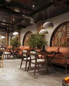 a restaurant with tables, chairs and potted plants on the wall behind them is decorated in an art deco style