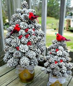 two pine cones are decorated as christmas trees