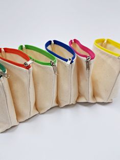 six zippered pouches lined up on a white surface, each with different colored handles