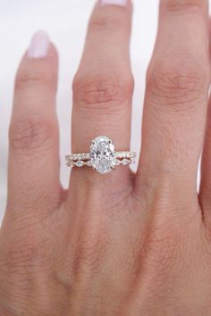 a woman's hand with a diamond ring on top of her finger and an engagement band