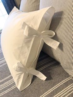 a white pillow tied to the back of a couch with a bow on it's side