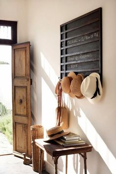 hats are hanging on the wall next to a wooden door and table with a hat rack