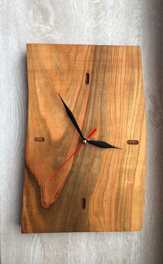 a clock made out of wood on top of a wooden table with black hands and red numbers