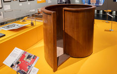 a wooden object on display in a museum with yellow flooring and glass cases behind it