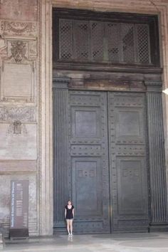 a woman standing in front of a large wooden door