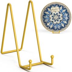 a blue and white plate sitting on top of a metal rack next to a gold stand