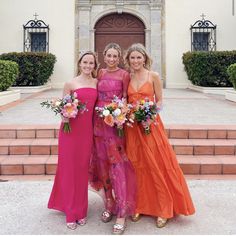 three beautiful women standing next to each other in front of a building with steps and flowers