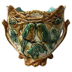 a ceramic vase with two birds sitting on it's sides and leaves around the edges