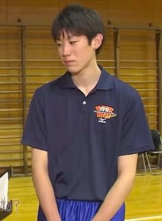 a young man standing on top of a basketball court wearing blue shorts and a black shirt