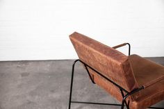 a wooden bench sitting on top of a black metal frame with a brown leather seat