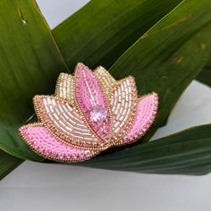 a pink brooch sitting on top of a green leaf