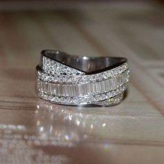 a wedding ring with three rows of diamonds on it's sides, sitting on top of a table