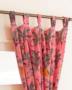 pink curtains with animals and plants on them hanging from a curtain rod in front of a window