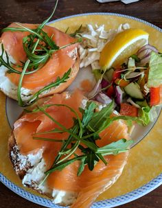 a plate with bread, salad and salmon on it sitting on top of a wooden table