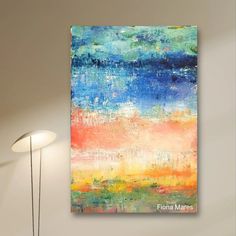 an abstract painting hangs on the wall above a lamp in a room with white walls