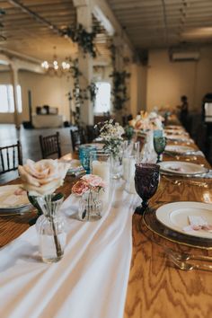 a long table is set with place settings and flowers in vases on the tables