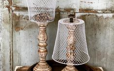 two old fashioned lamps sitting on top of a wooden table next to an old door