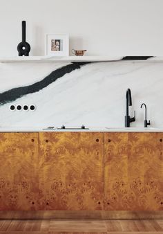 a kitchen with white marble counter tops and wooden cabinetry, along with black faucets