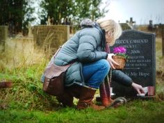 a woman kneeling down in front of a grave