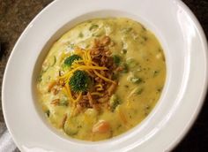 a white bowl filled with broccoli and cheese soup on top of a table