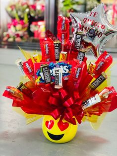 a smiley face vase filled with candy and balloons