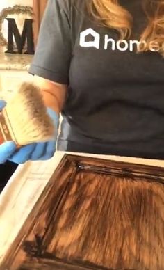 a woman is using a brush to clean an old wooden cabinet door with wood stain