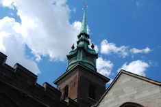 a tall tower with a clock on it's side against a blue sky filled with clouds