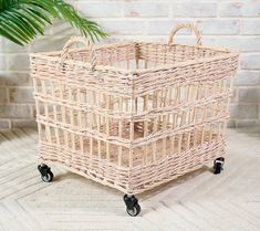 a wicker basket sitting on wheels in front of a brick wall with a potted plant