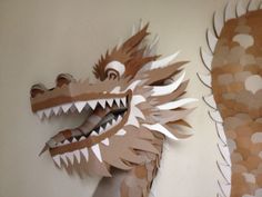 a paper sculpture of a dragon on the wall next to another one with its mouth open